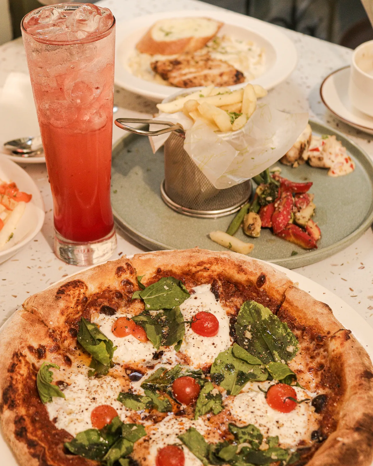 Pizza, fries and drinks on a terrazzo table